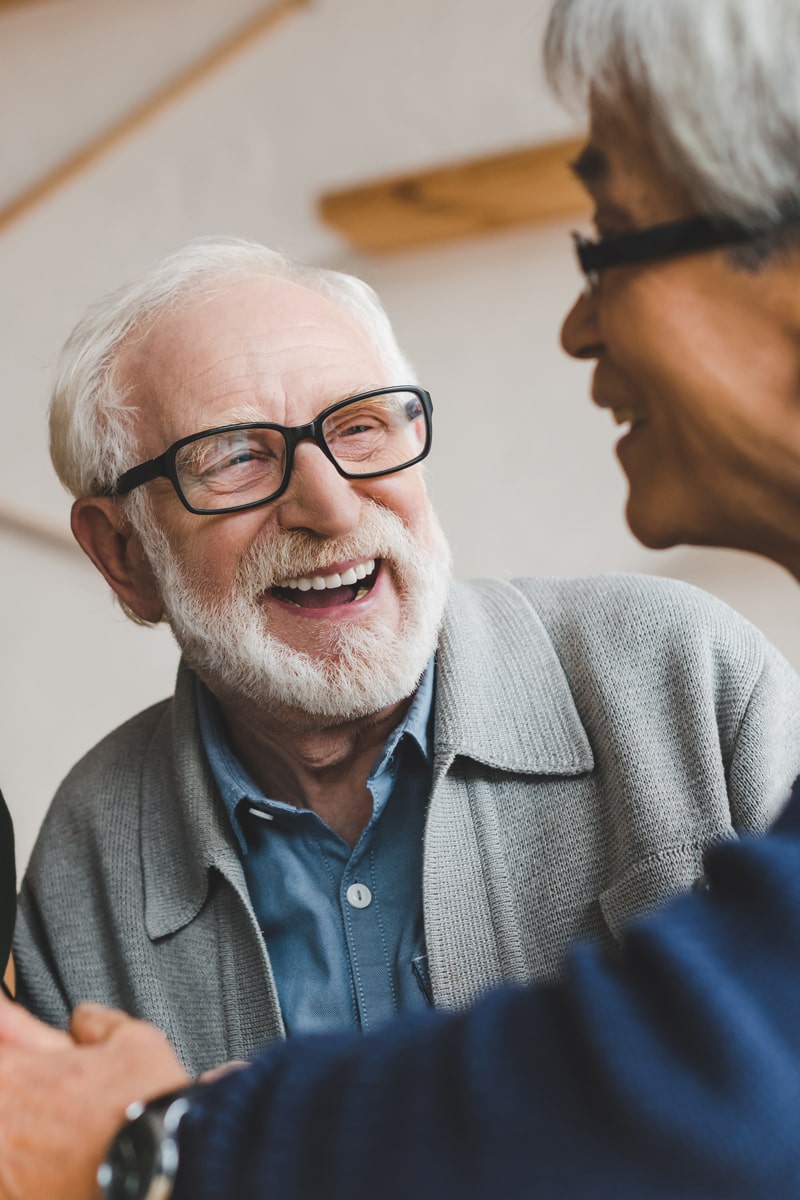 Elderly man smiling and laughing with his friend.